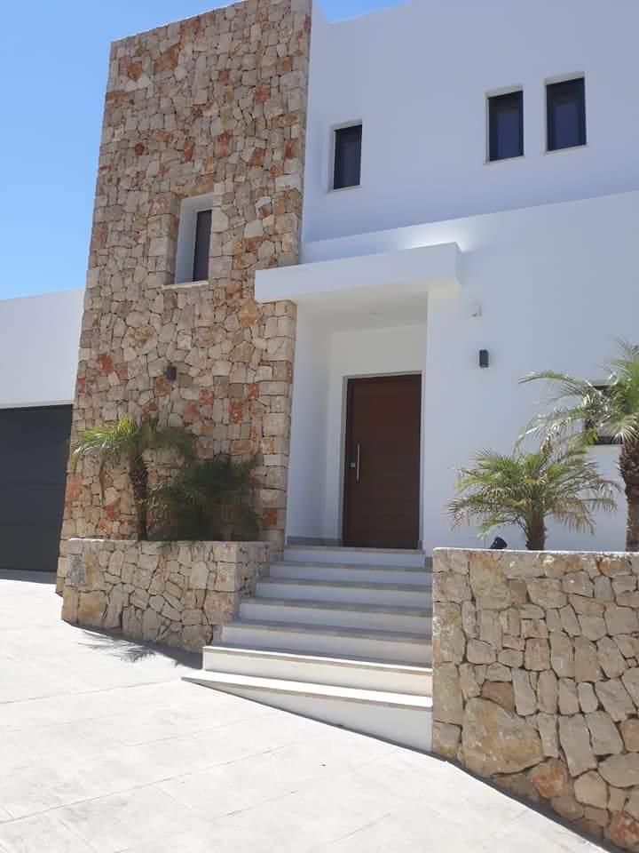 Una casa blanca con un muro de piedra y escaleras