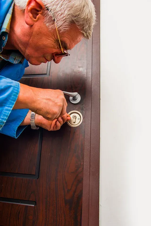 Un hombre está arreglando una puerta con un destornillador.