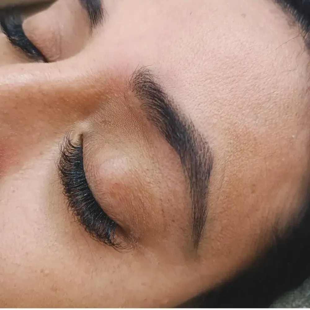 Primer plano del ojo cerrado de una persona, con pestañas abundantes y cejas oscuras y bien definidas.