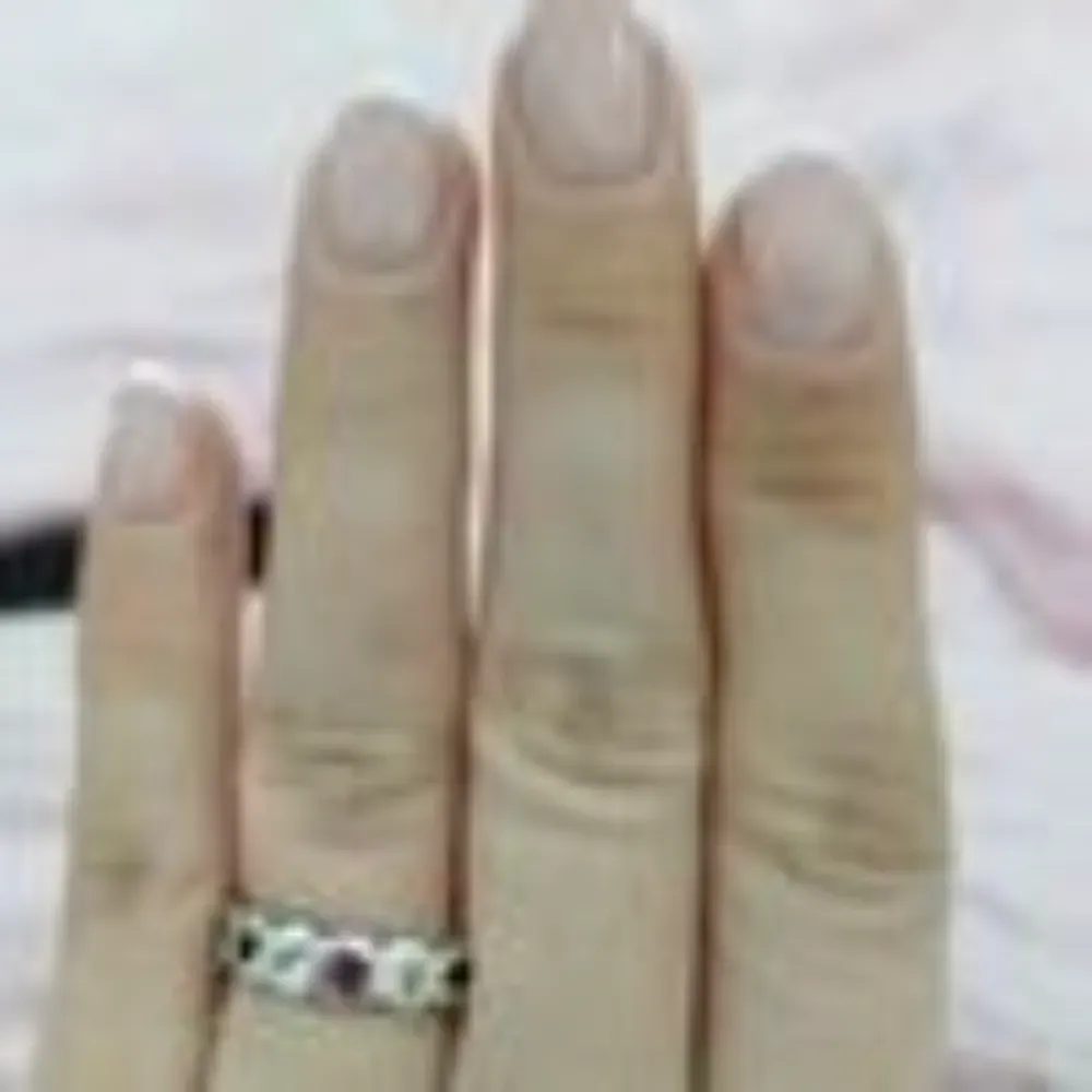 Mano con un anillo en el dedo. El anillo tiene gemas y un diseño floral.