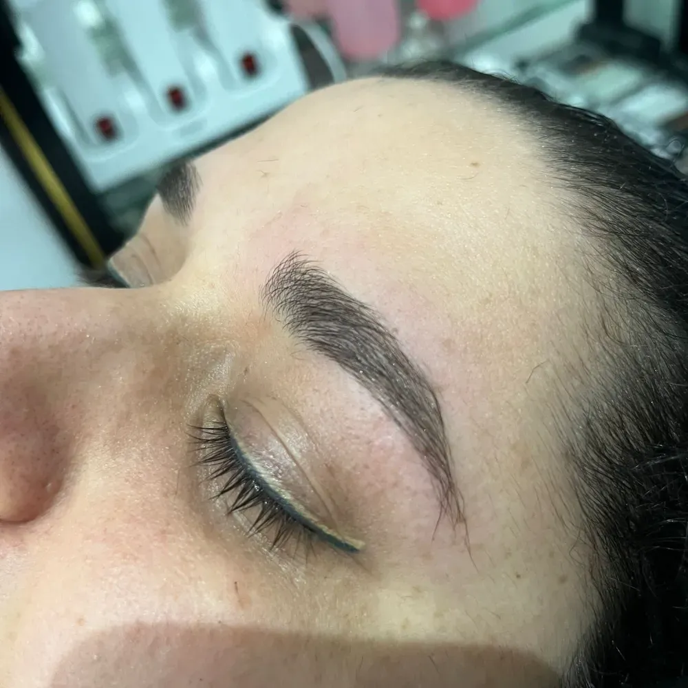 Primer plano de la ceja de una persona después de un tratamiento de cejas, mostrando una forma definida.