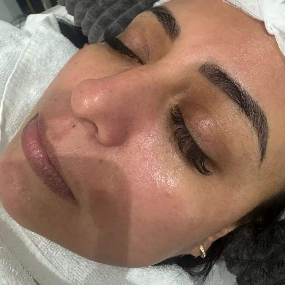 Mujer con ojos cerrados, labios carnosos y cejas oscuras, descansando sobre una toalla blanca.
