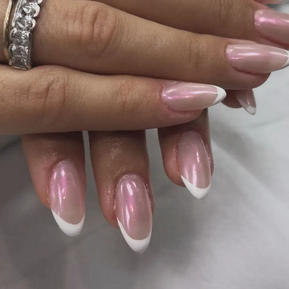 Manos con uñas en forma de almendra con base de color rosa perlado y puntas francesas blancas.