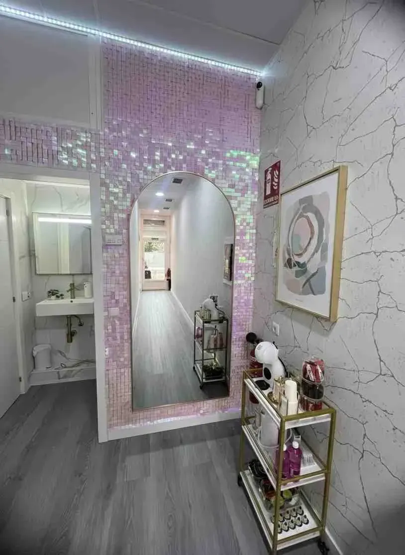 Pasillo estrecho de salón con un gran espejo, carrito de exhibición y pared decorativa.