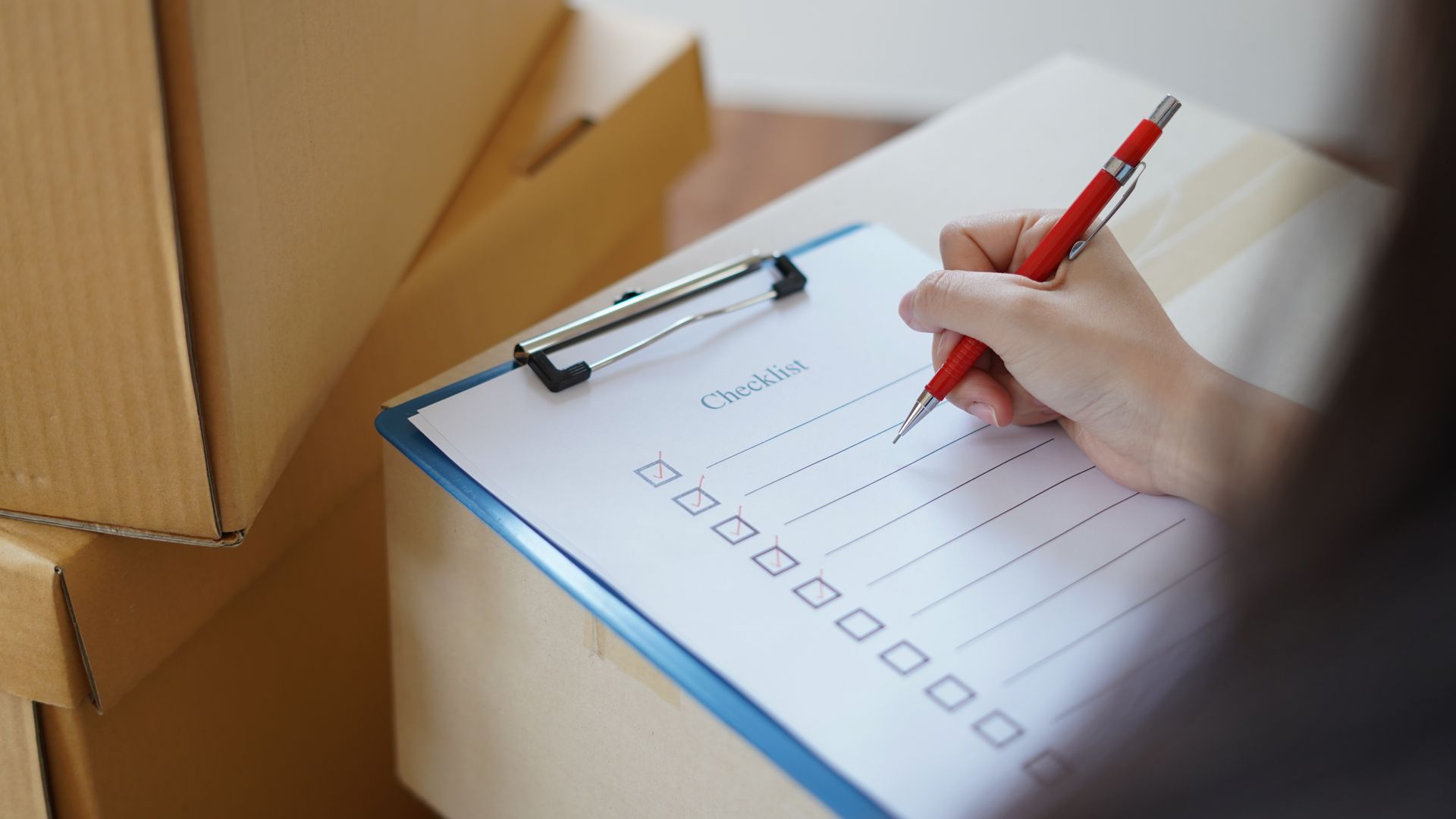 Une femme remplit une checklist sur un carton de déménagement