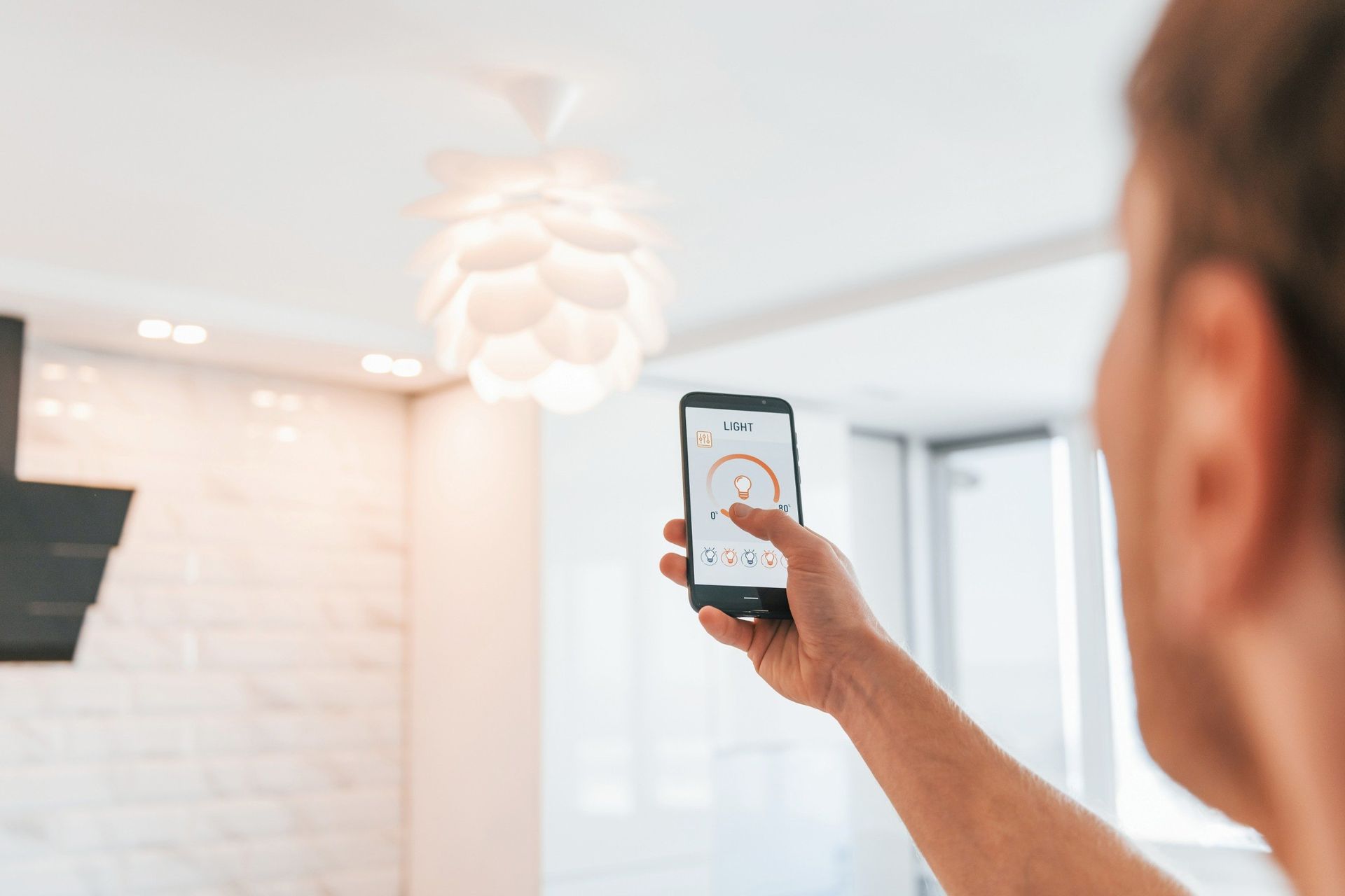 Un hombre sostiene un teléfono inteligente en su mano en una cocina.