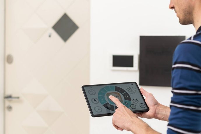Un hombre está usando una tableta para controlar una casa inteligente.