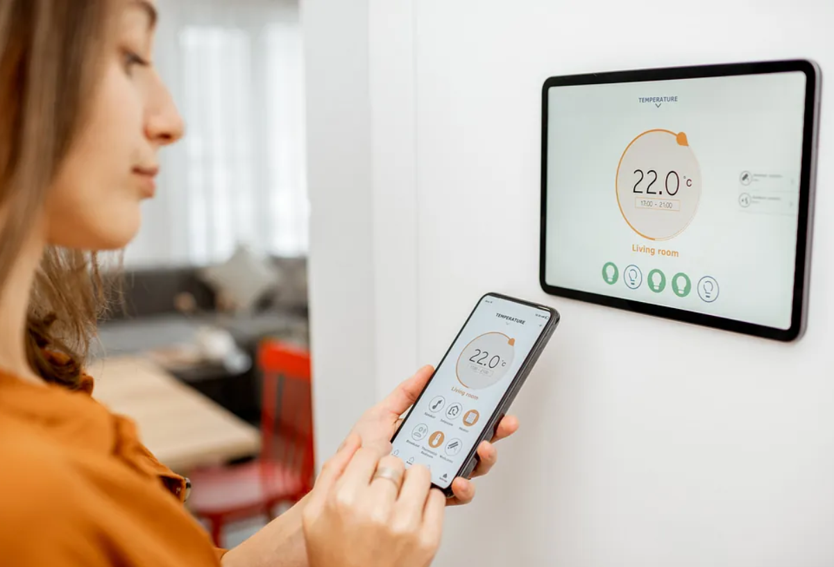 Una mujer está usando un teléfono inteligente para controlar un termostato.