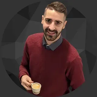Un hombre con un suéter rojo sostiene una taza de café.