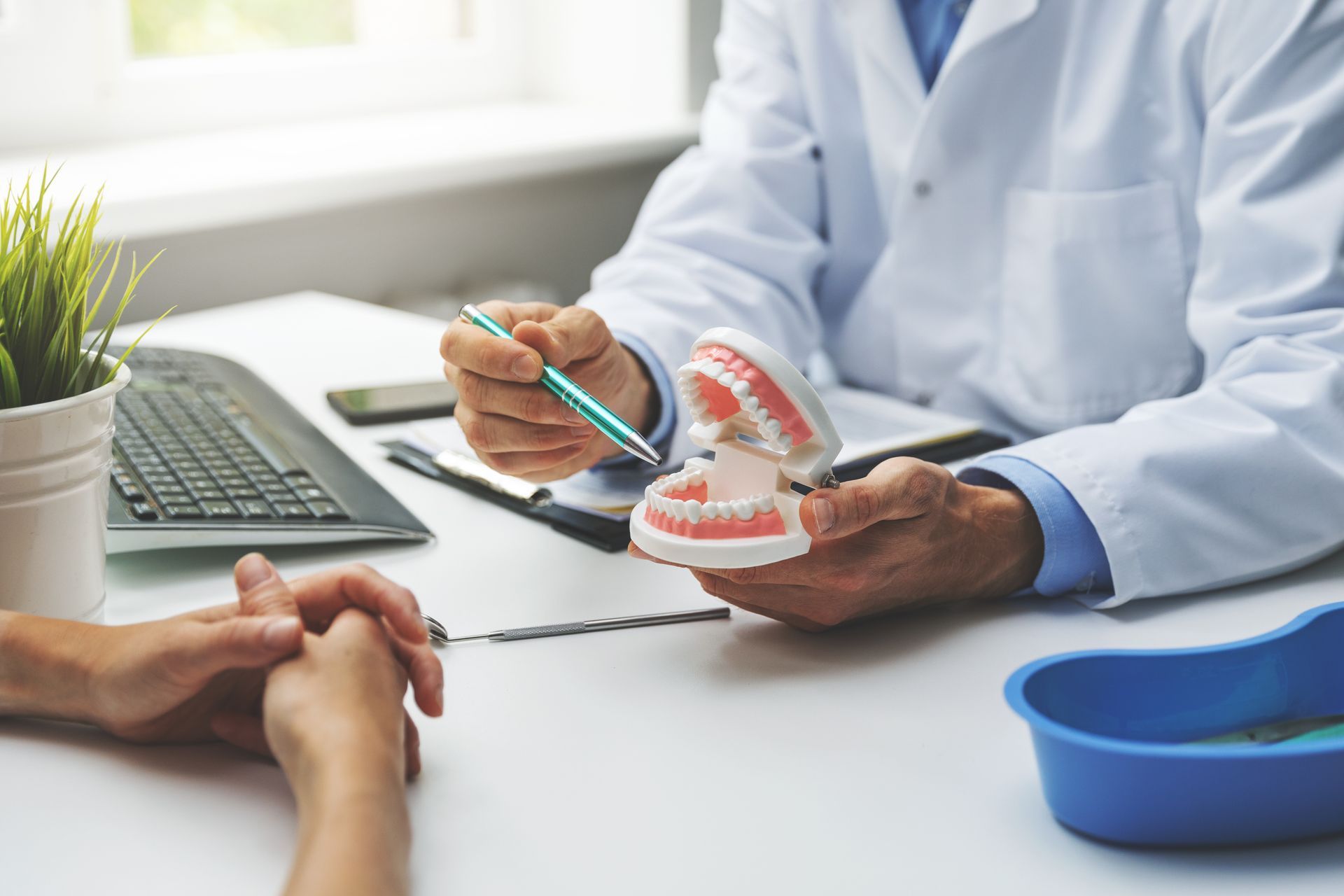 Un dentiste explique un modèle dentaire à un patient au bureau de sa clinique.