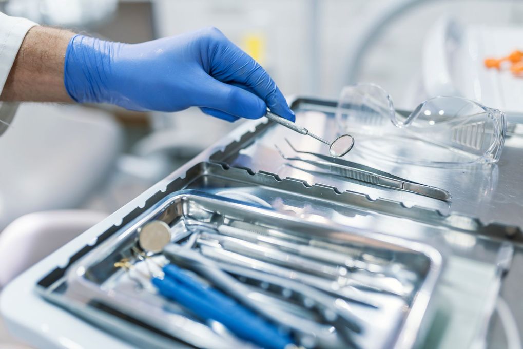 Main gantée saisissant des instruments dentaires dans un plateau stérilisé