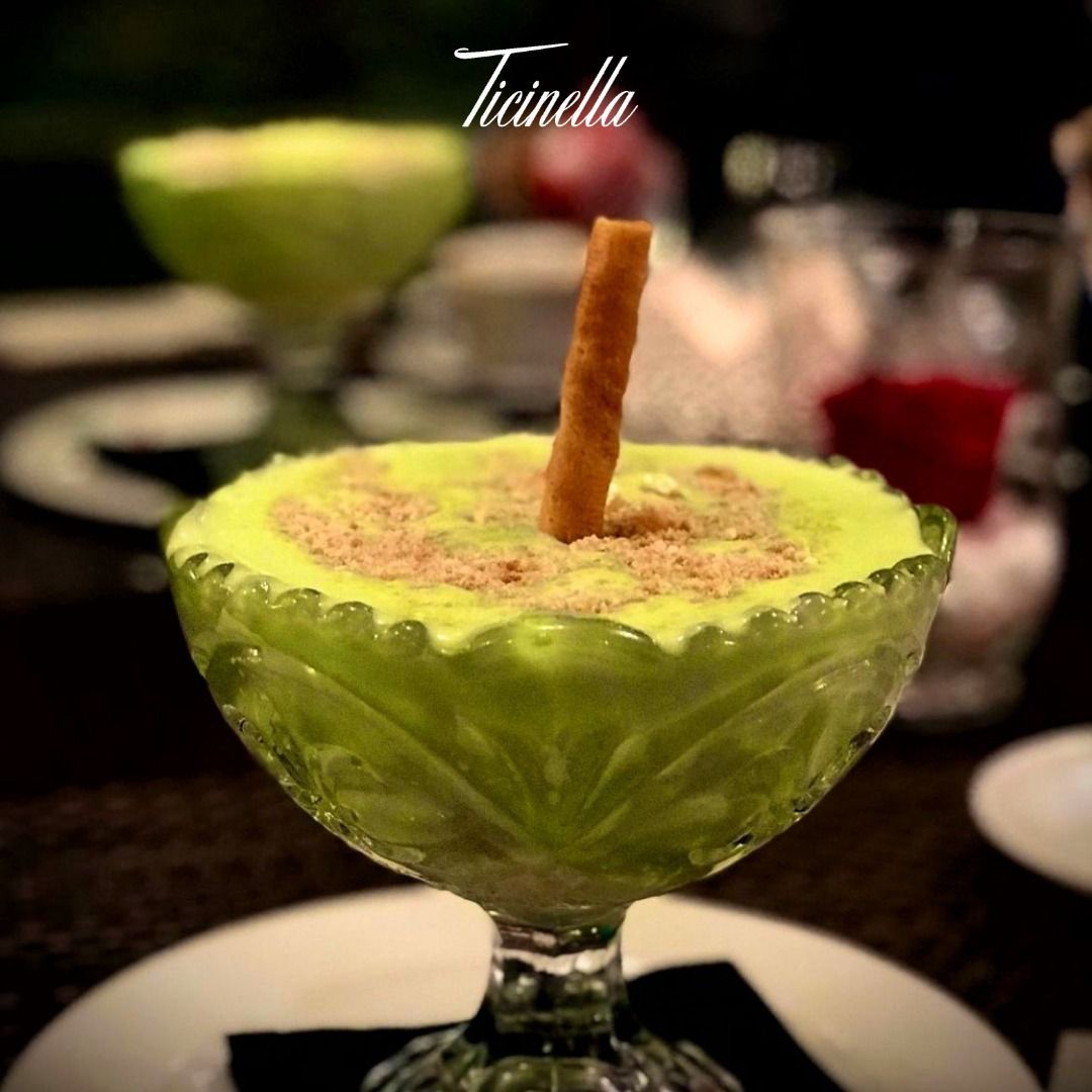 Un bicchiere di gelato verde con un bastoncino di cannella dentro