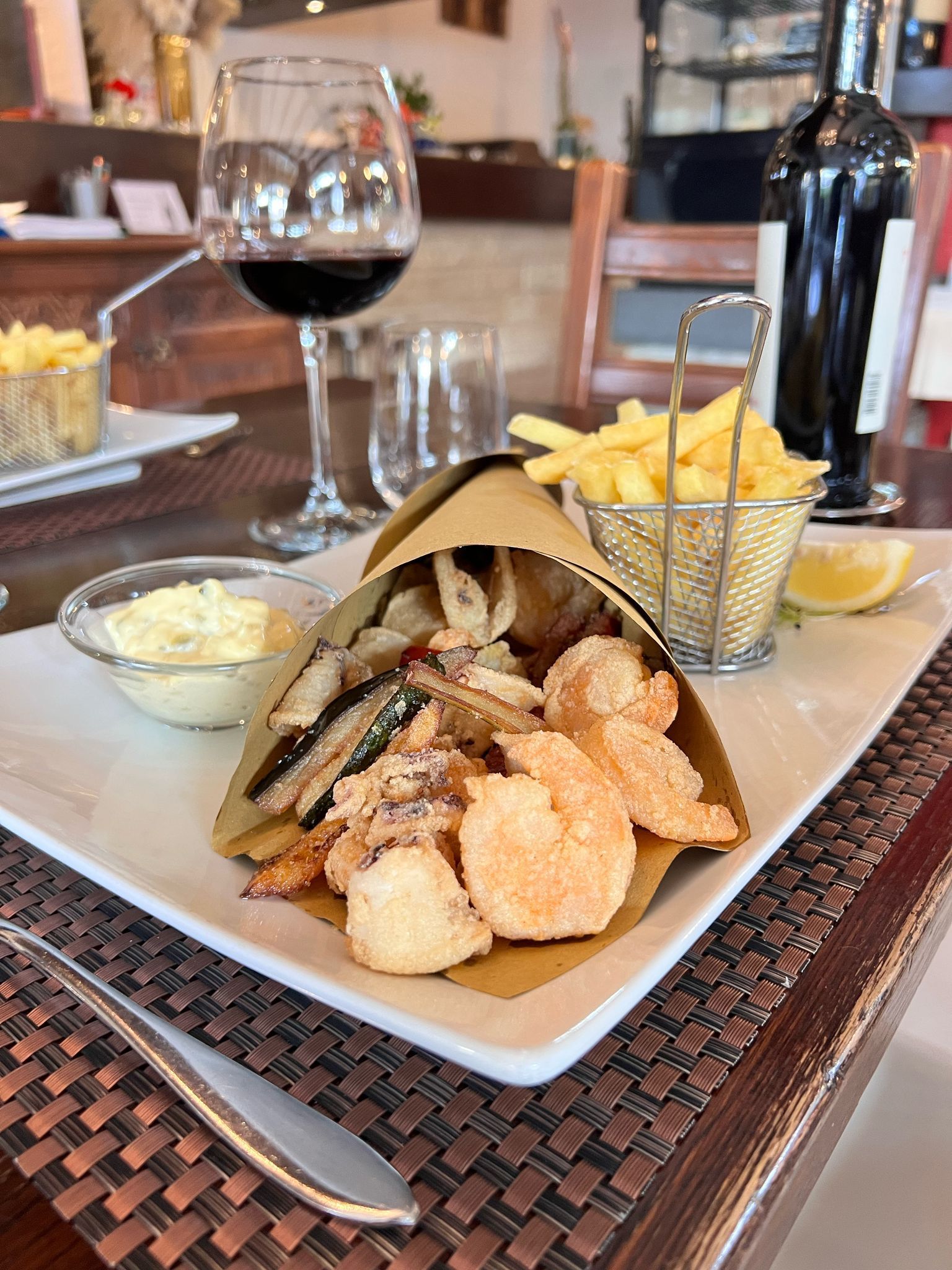 Un piatto di cibo con patatine fritte e un bicchiere di vino su un tavolo.