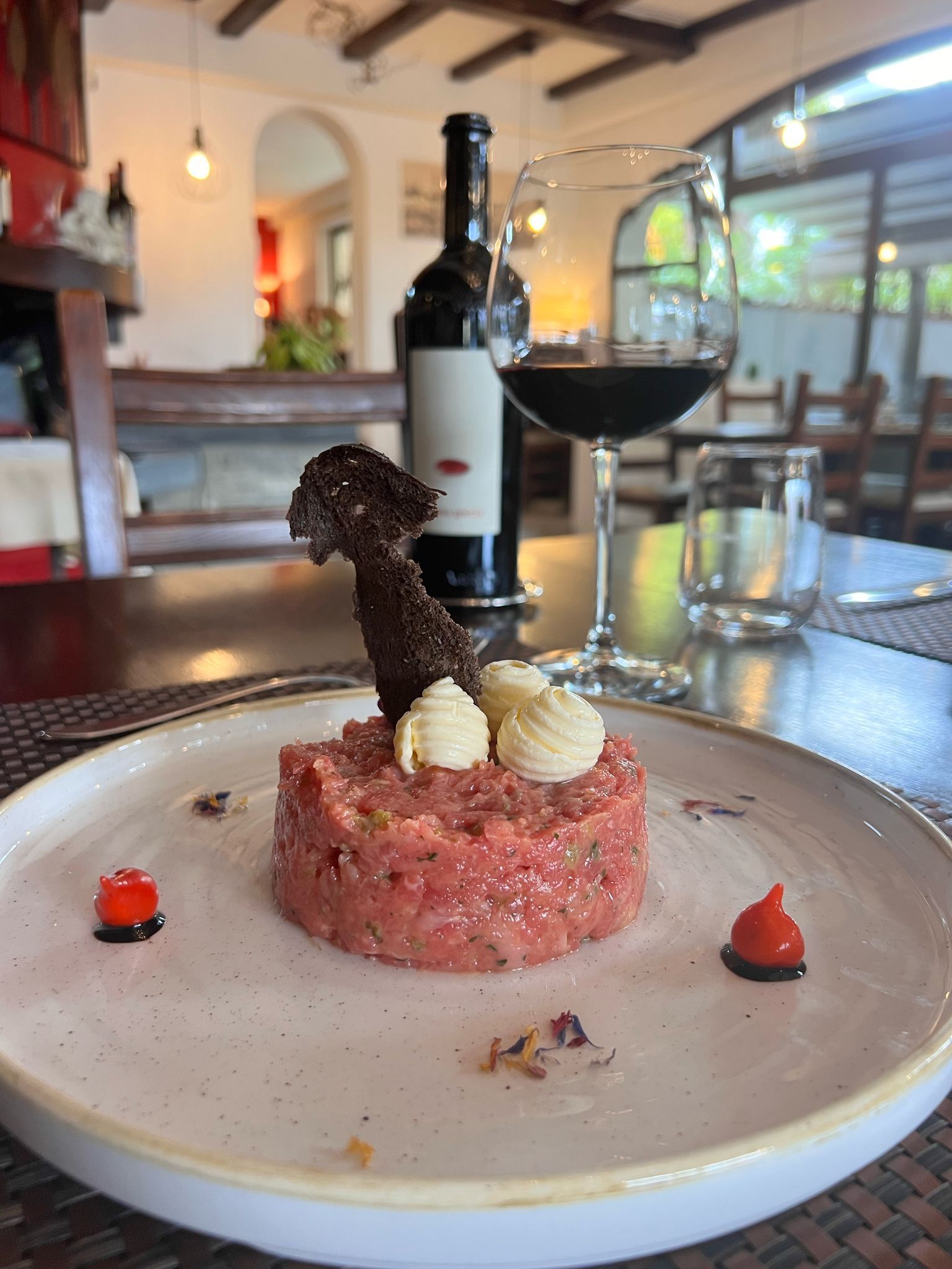 Un piatto di cibo è sul tavolo accanto a un bicchiere di vino e una bottiglia di vino.