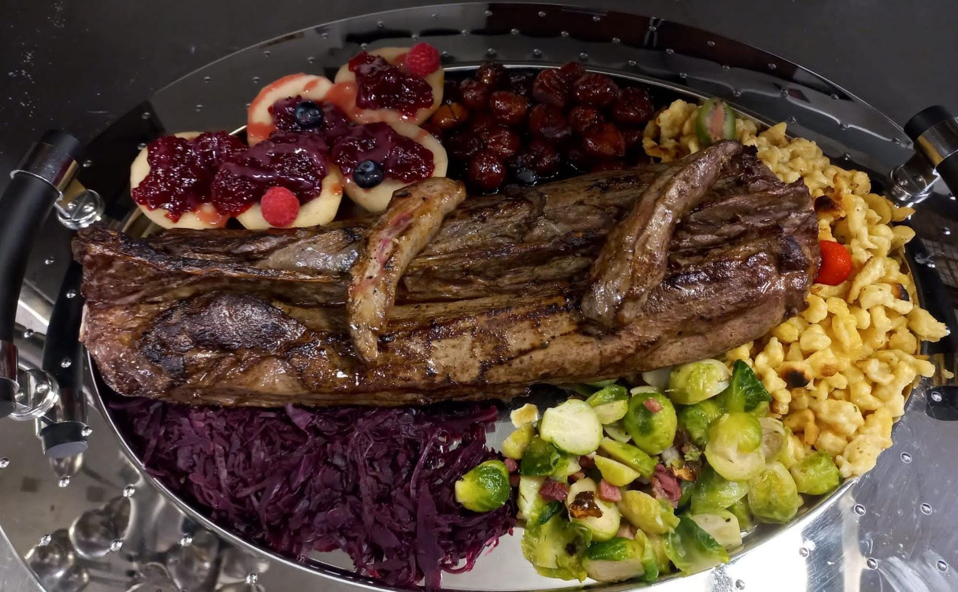 Un piatto di cibo con carne, verdure e frutta su un tavolo.