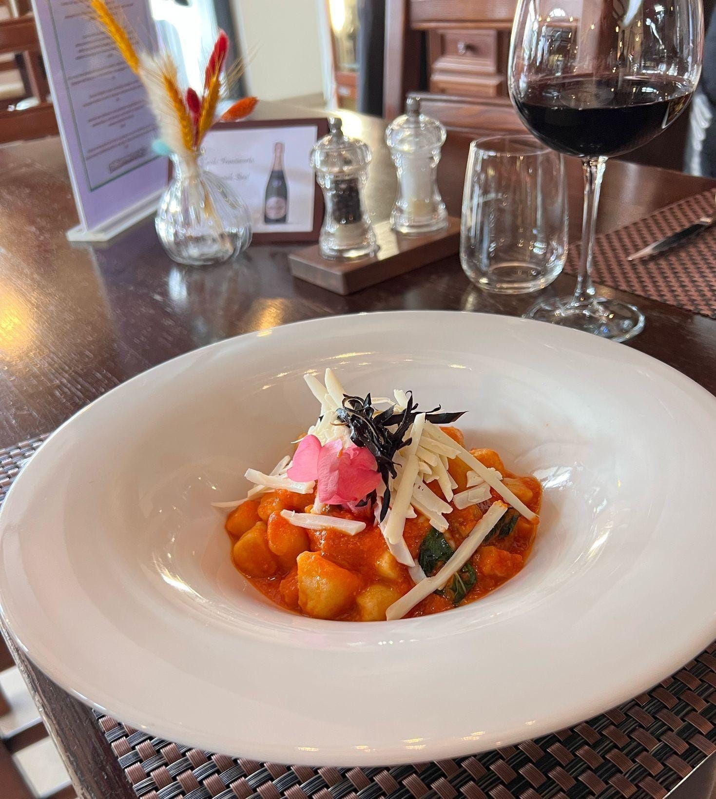 Un piatto di cibo su un tavolo accanto a un bicchiere di vino