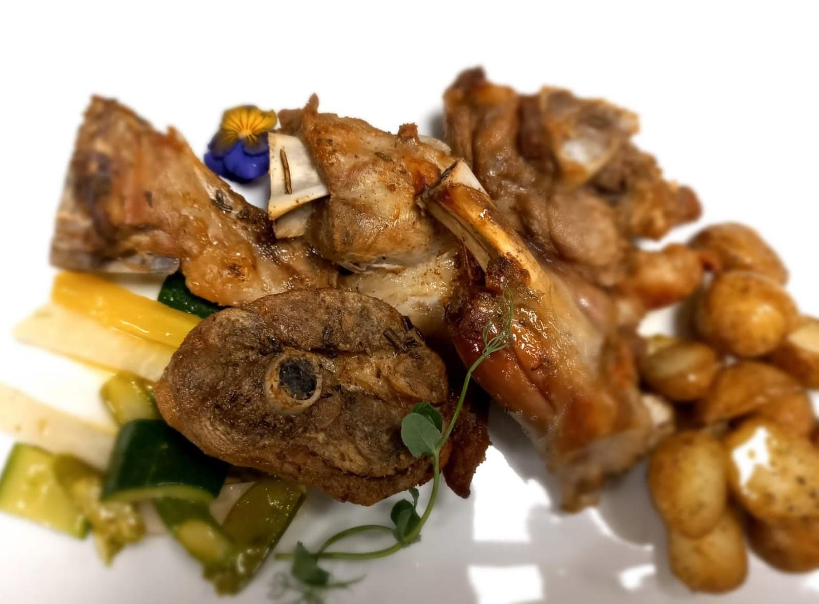 Un piatto bianco con sopra carne e verdure su un tavolo.