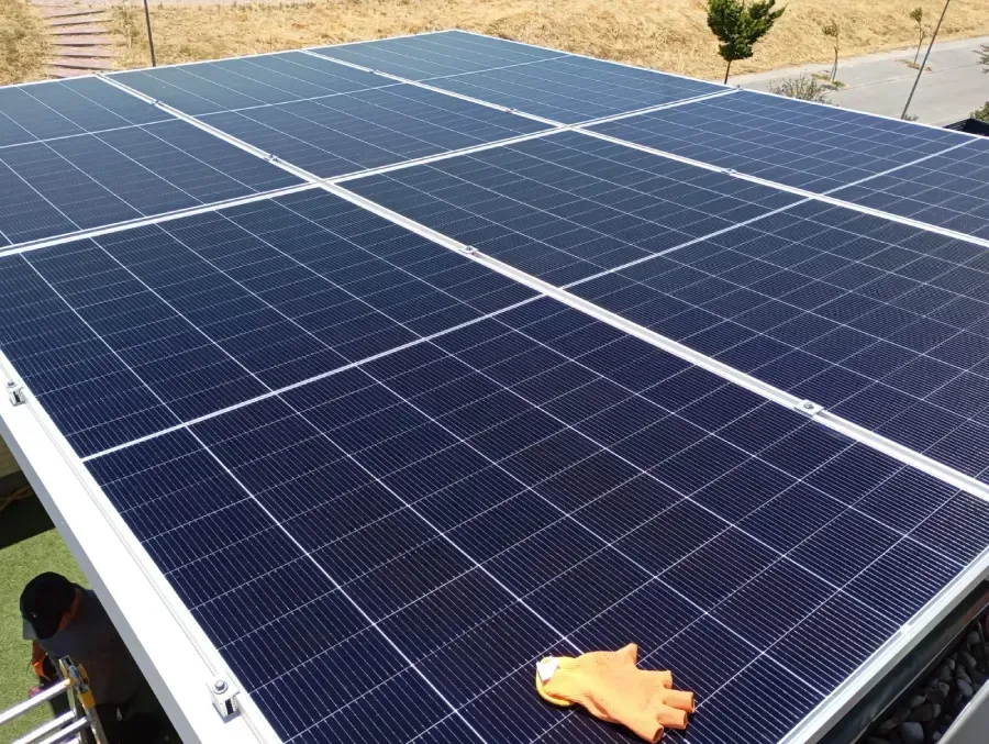 Filas de paneles solares azules con una mano sosteniendo un paño para limpiar o inspeccionar.