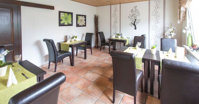 Ein Esszimmer mit Tischen und Stühlen, die für eine Mahlzeit aufgestellt sind.