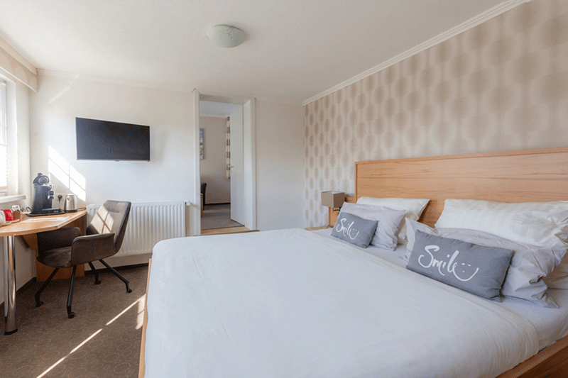 Ein Hotelzimmer mit Bett, Stuhl, Schreibtisch und Fernseher.