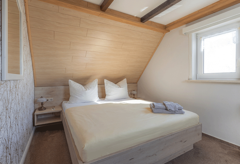Ein Schlafzimmer mit zwei Betten, einem Stuhl, einem Tisch und einem Fernseher.