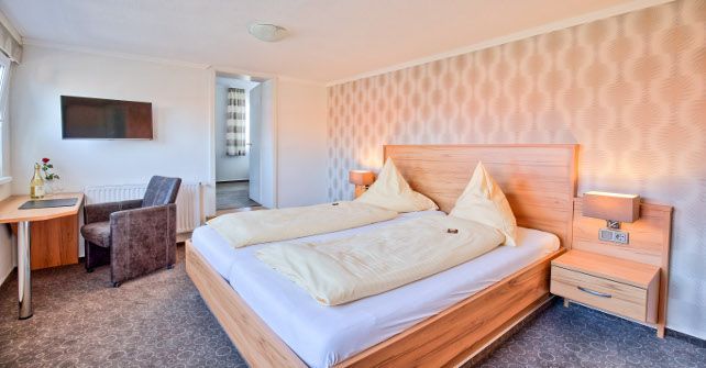 Ein Hotelzimmer mit Bett, Stuhl, Schreibtisch und Fernseher.