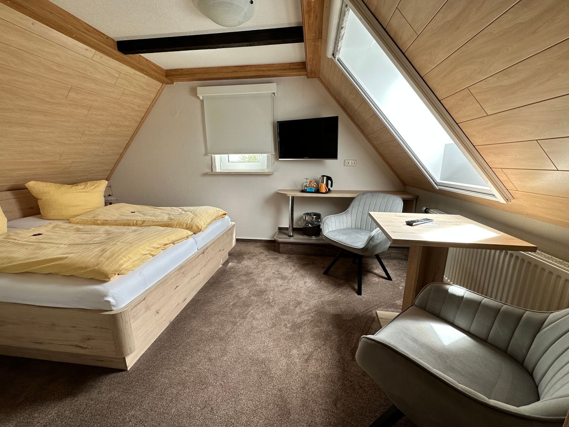 Ein Schlafzimmer mit Bett, Stuhl, Schreibtisch und Fernseher.