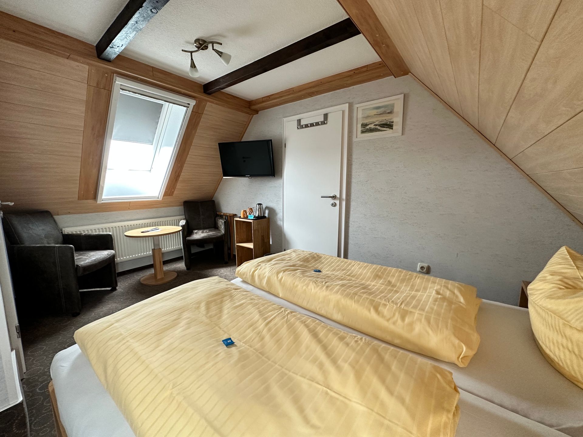 Ein Schlafzimmer mit zwei Betten, einem Stuhl, einem Tisch und einem Fernseher.