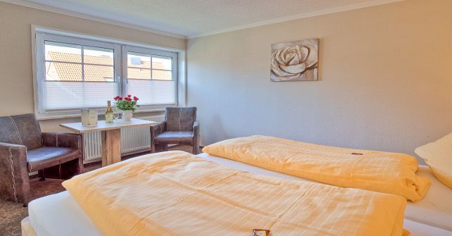 Ein Schlafzimmer mit zwei Betten, einem Tisch und Stühlen.