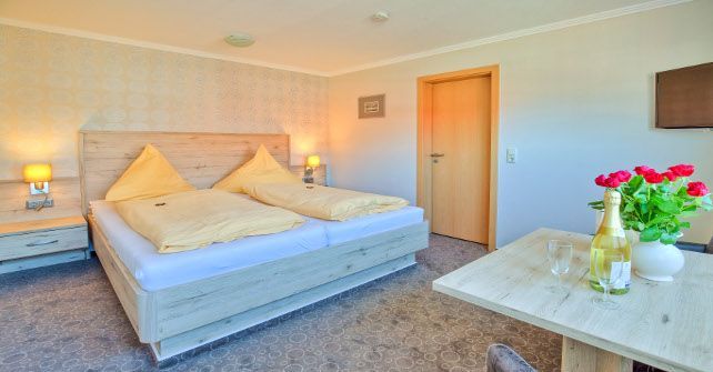 Ein Hotelzimmer mit Bett, Tisch, Stühlen und einer Flasche Wein.