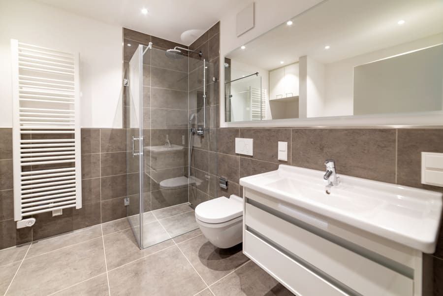 Salle de bains moderne avec douche à l'italienne, toilettes et meuble-lavabo blanc avec miroir.