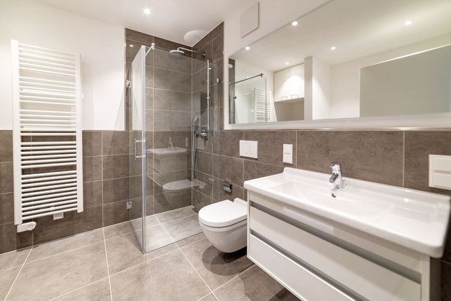 Salle de bains moderne blanche avec douche à l'italienne, lavabo, miroir mural et sèche-serviettes