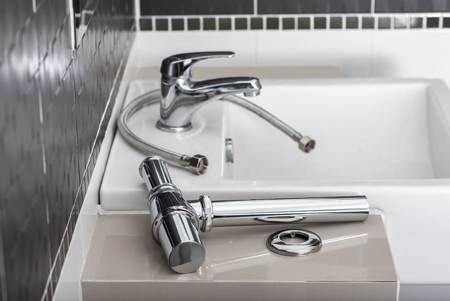Lavabo de salle de bain avec robinet chromé, flexible de douche amovible et bouchon de lavabo sur le comptoir