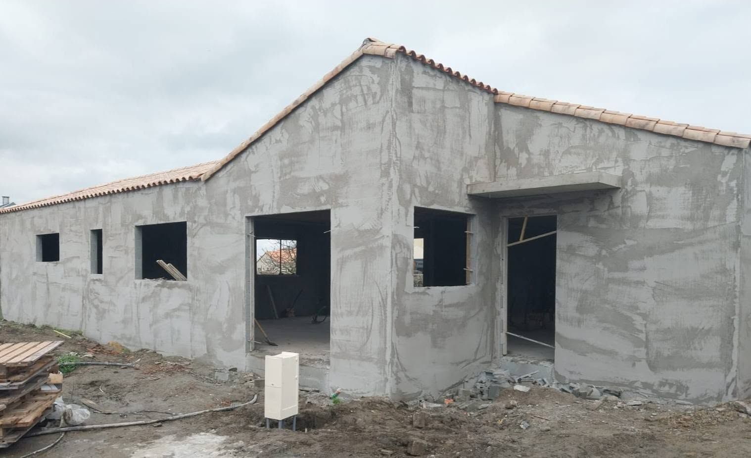 Maison en béton gris inachevée, avec des ouvertures pour les fenêtres et les portes 