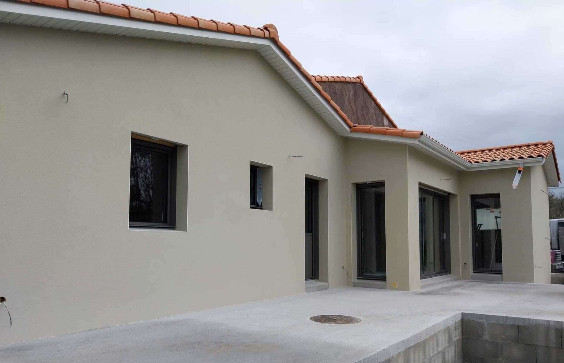 Maison moderne beige avec toit de tuiles rouges et de nombreuses fenêtres
