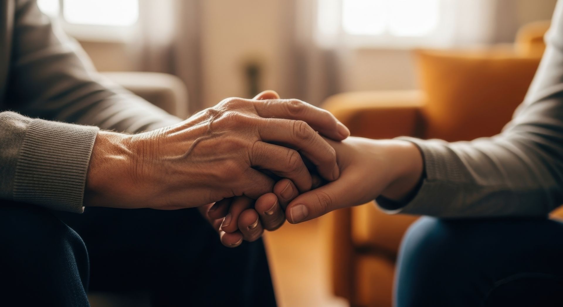 Mains jointes, une personne âgée tient une personne plus jeune. Confort et soutien sont au rendez-vous.