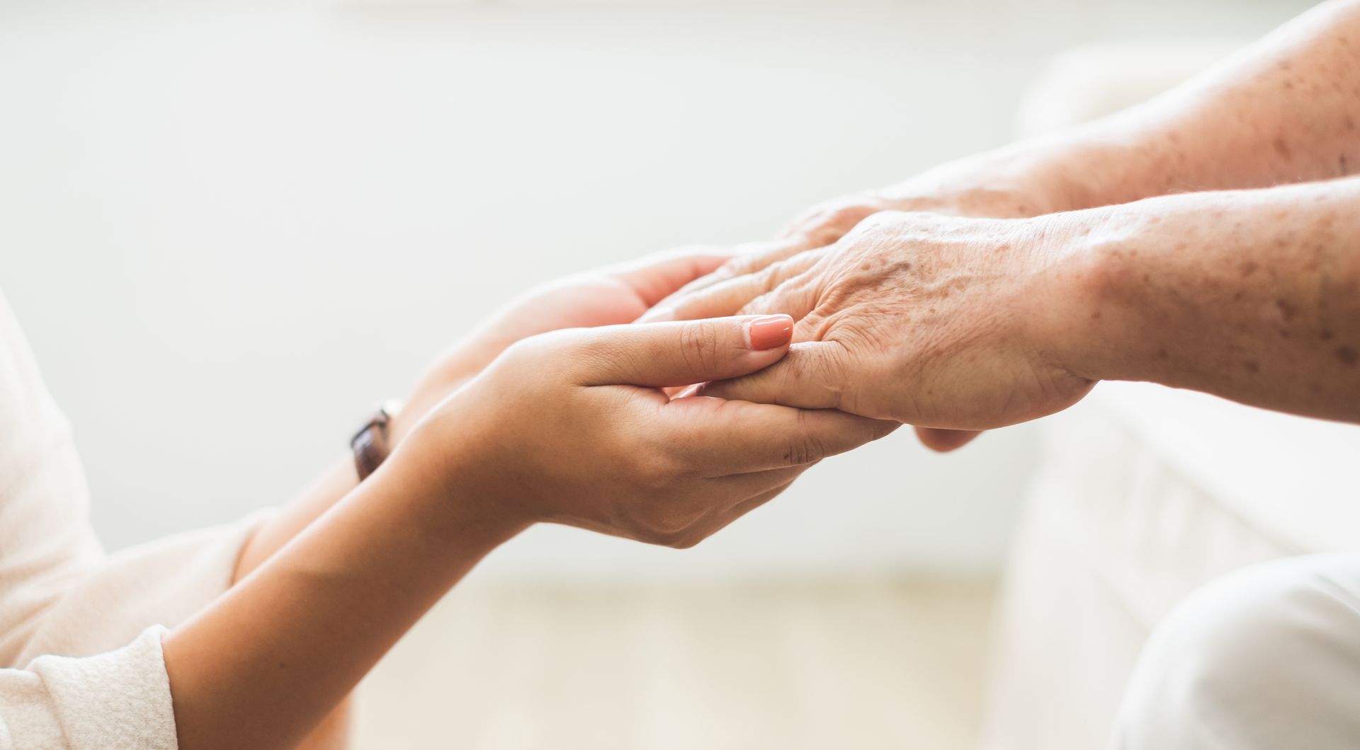 Une jeune maintient la main ridée d’une personne âgée, lui apportant réconfort et soutien.