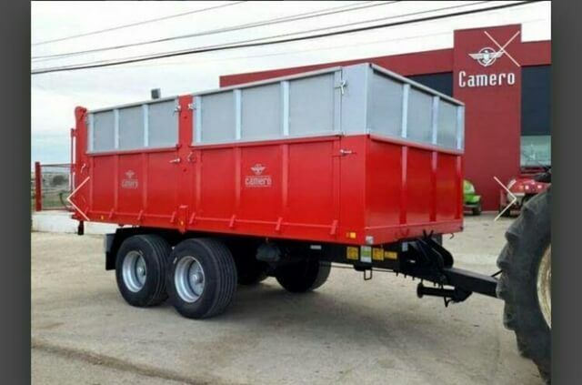 Un remolque rojo está estacionado frente a un edificio de cámaras.