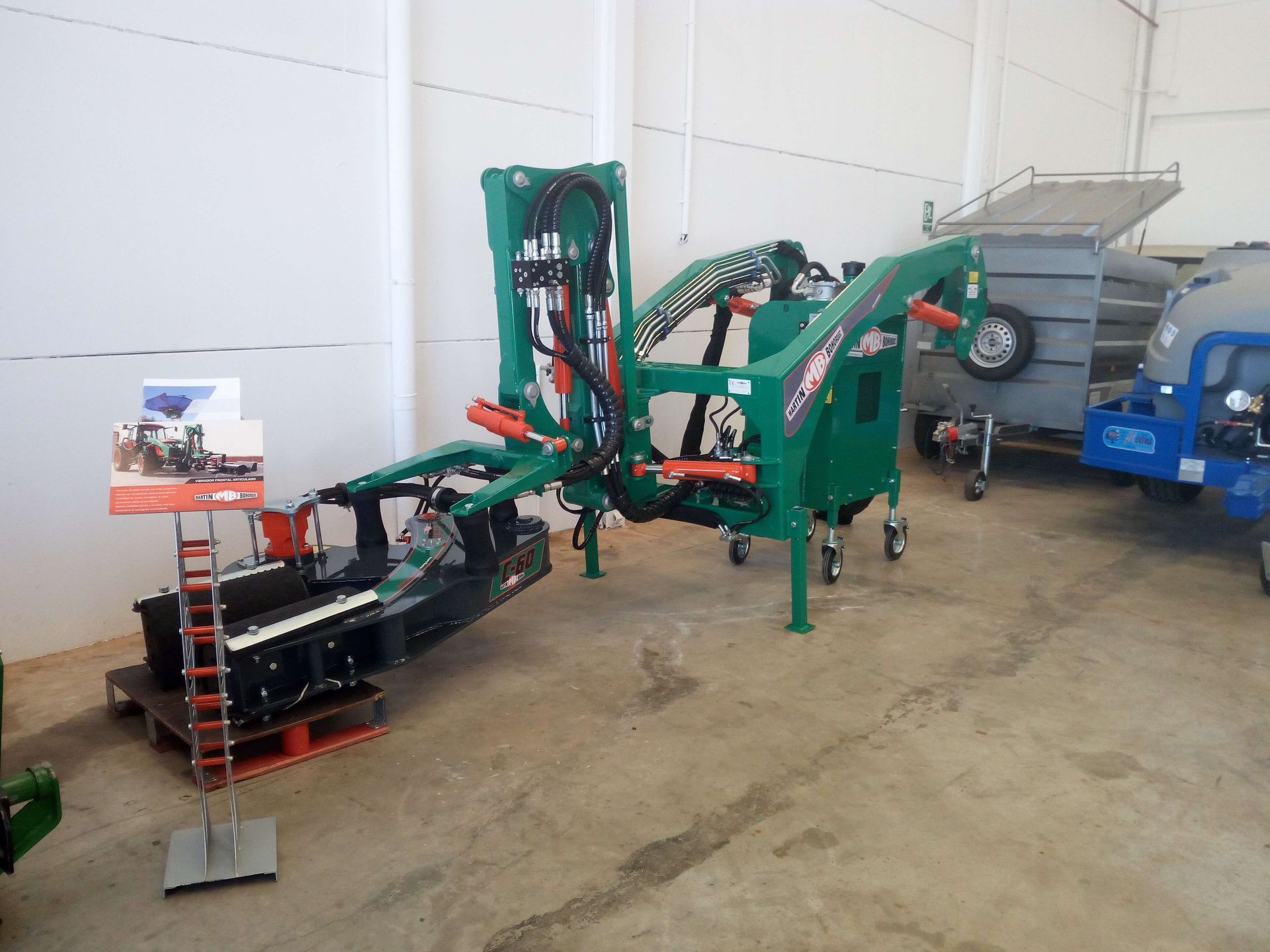 Una máquina verde está en un almacén con otras máquinas.