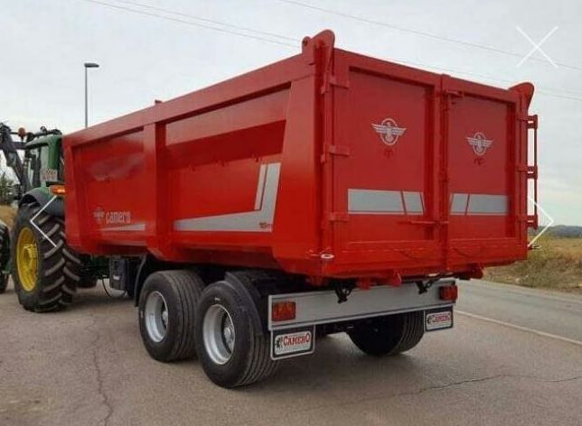 Un camión volquete rojo está estacionado junto a un tractor.