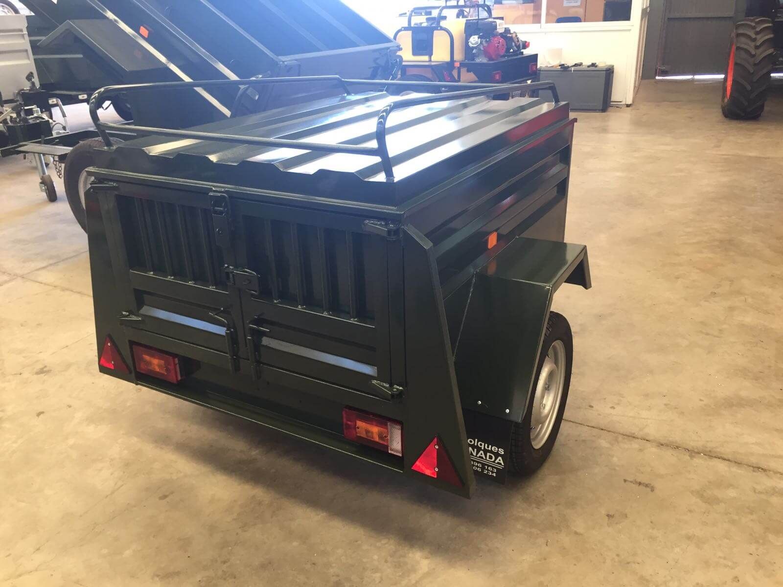 Un remolque negro con portaequipajes está estacionado en un garaje.