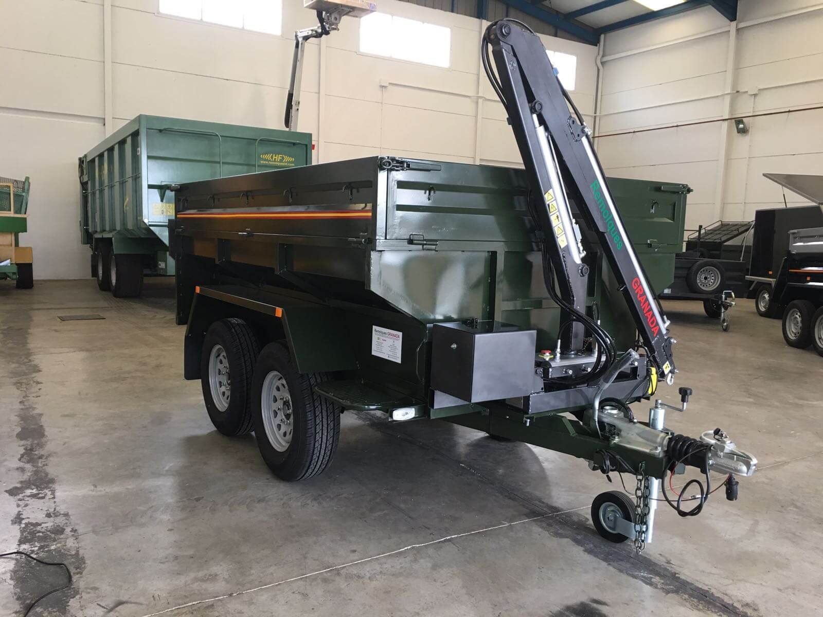 Un remolque con una grúa acoplada está estacionado en un almacén.