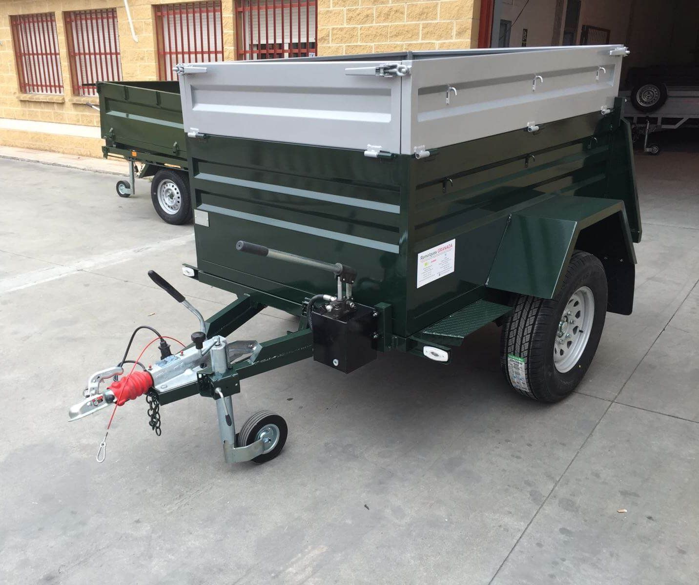Un remolque verde está estacionado al costado de la carretera frente a un edificio.