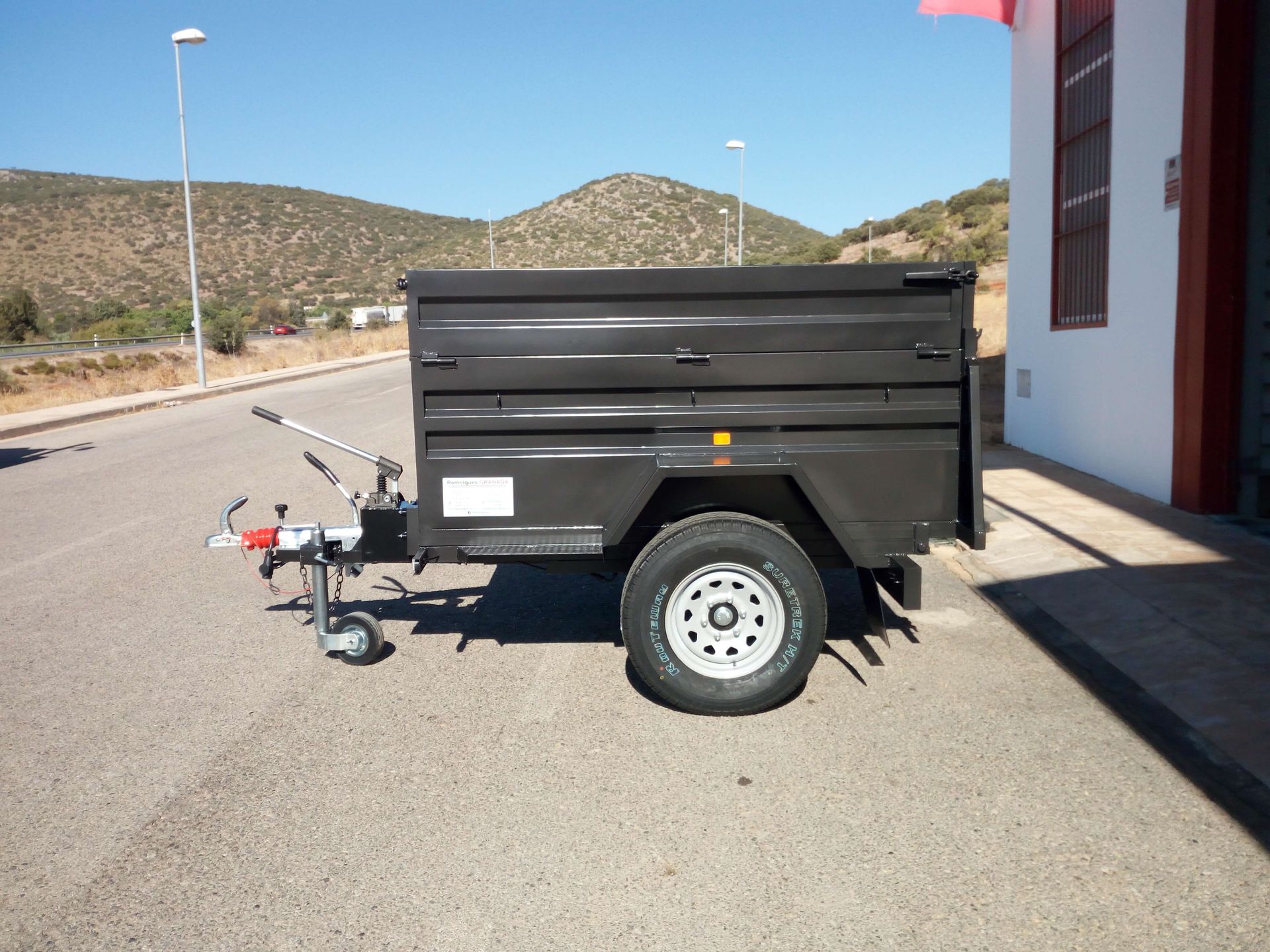 Un remolque negro está estacionado al costado de la carretera.