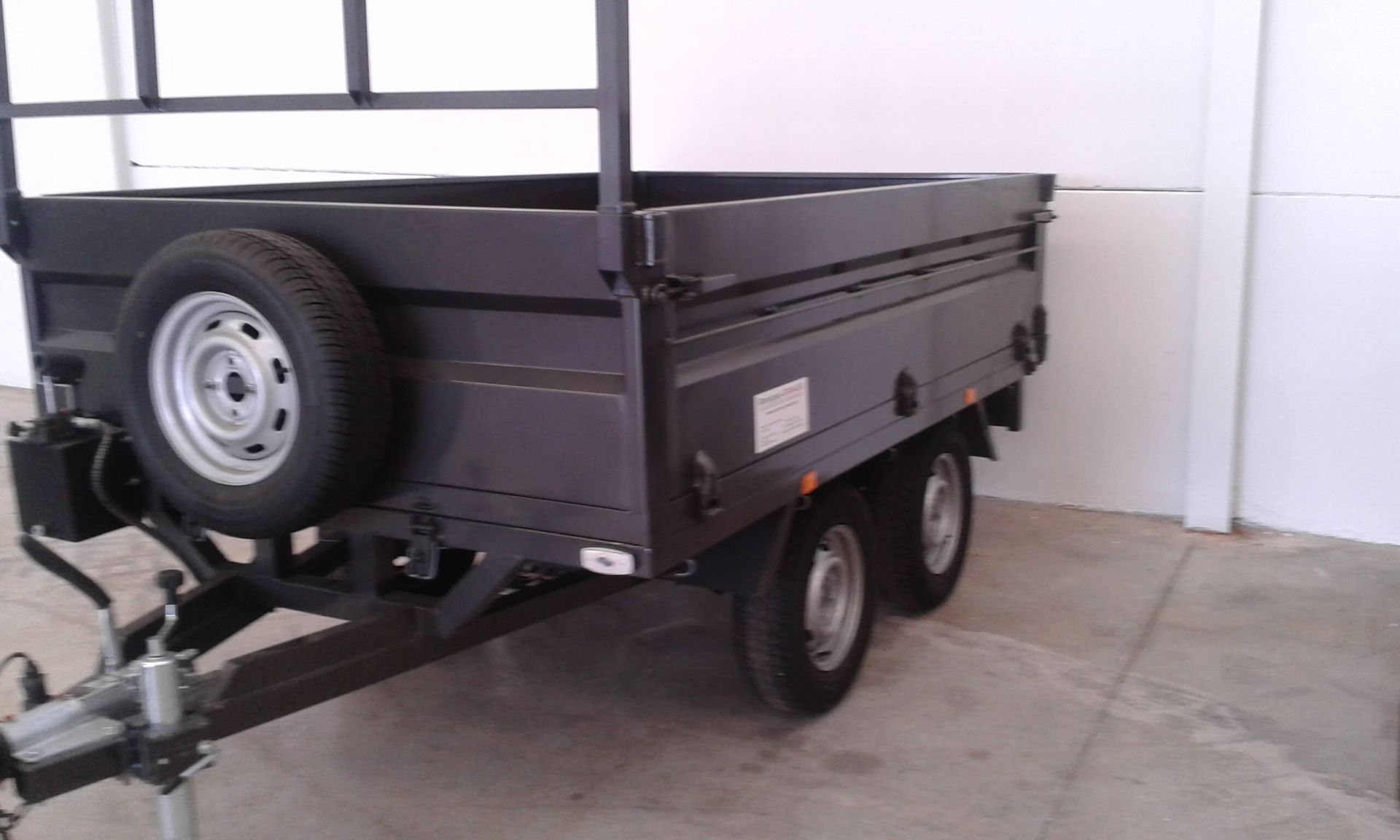 Un remolque negro con una llanta de repuesto en la parte trasera