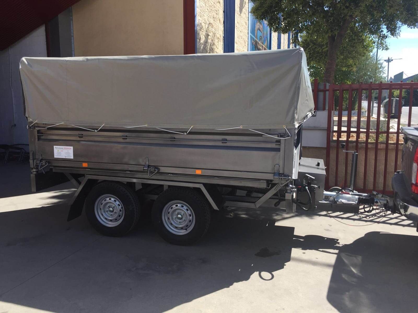 Un remolque con toldo está estacionado frente a un edificio.