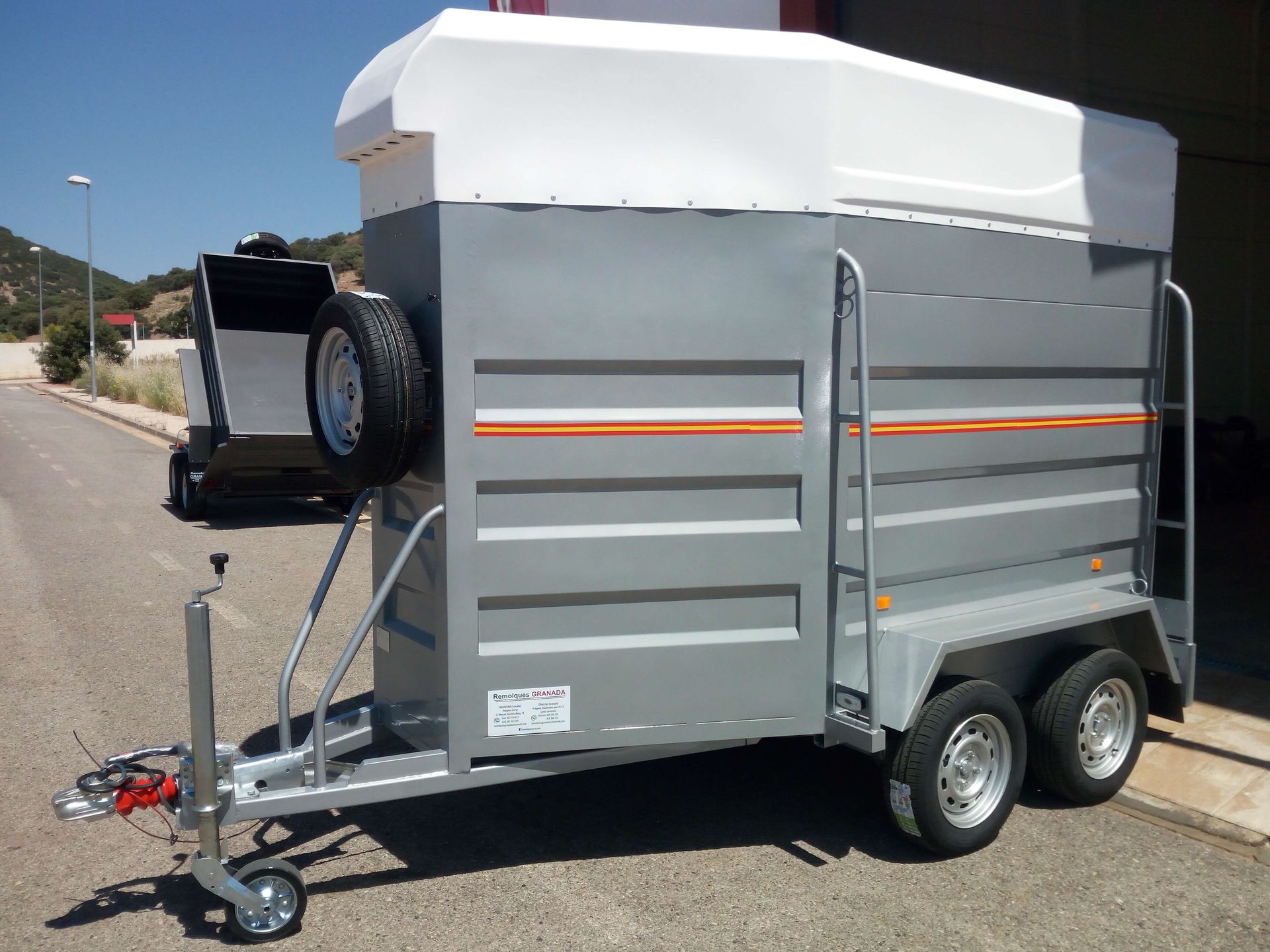 Un remolque con techo blanco está estacionado al costado de la carretera.