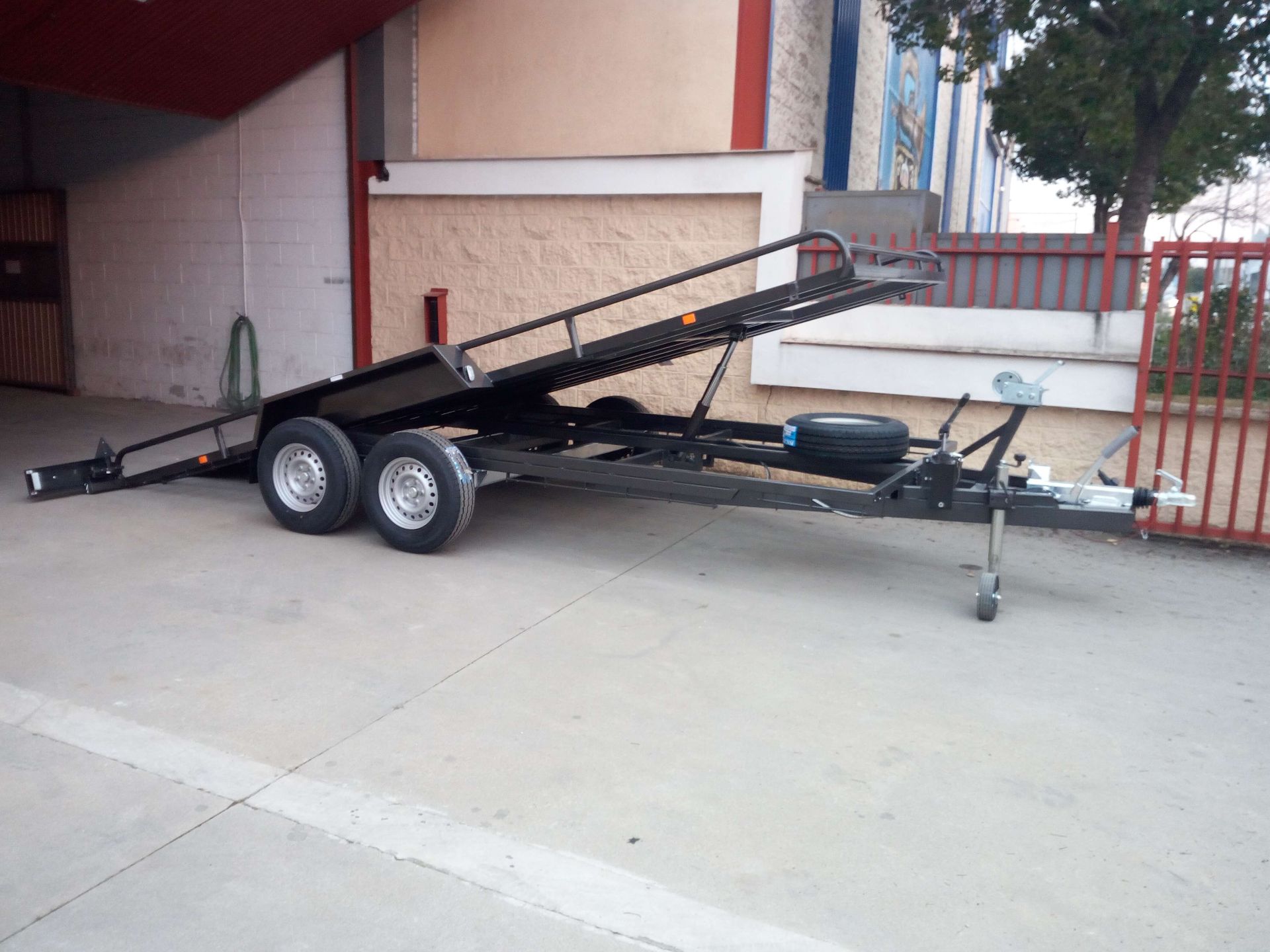 Un remolque negro está estacionado frente a un edificio.