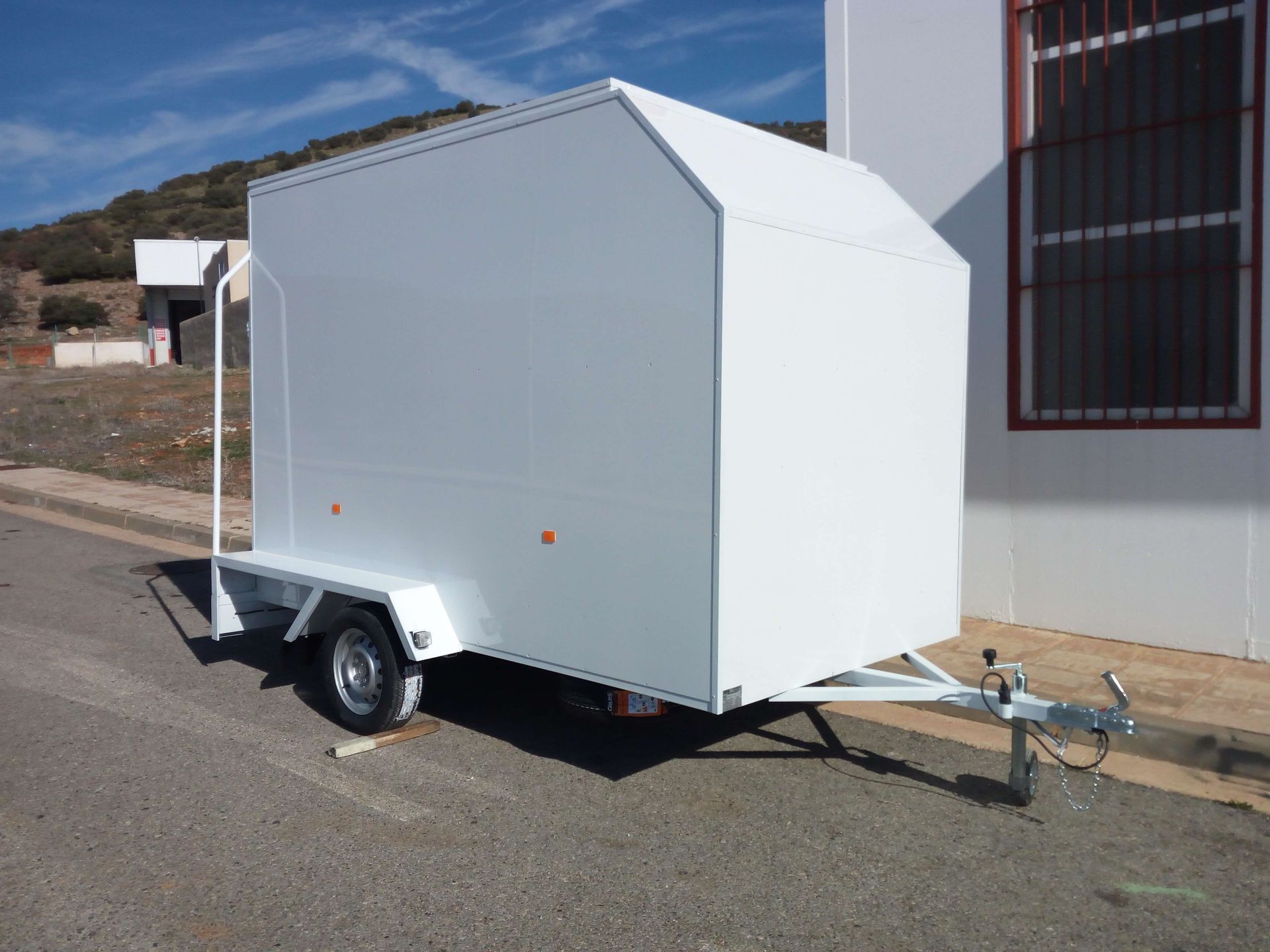 Un remolque blanco está estacionado al costado de la carretera.