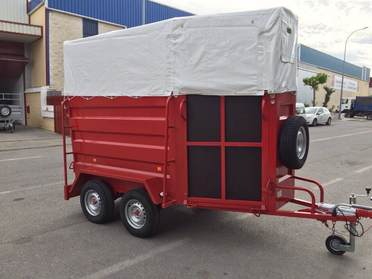 Un remolque rojo con una lona blanca encima está estacionado en un estacionamiento.